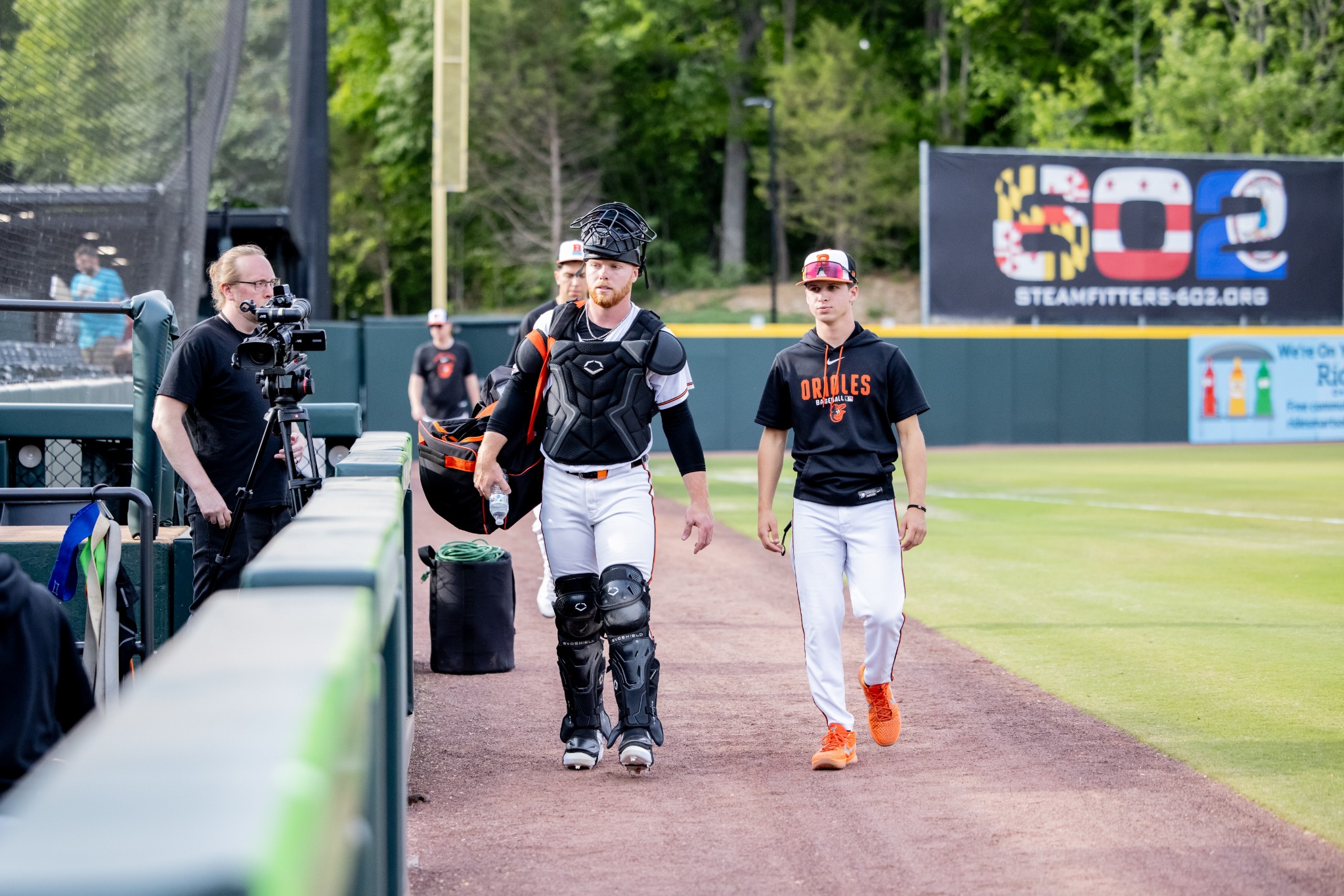 Coach Bernie walking alongside a catcher on the baseball field